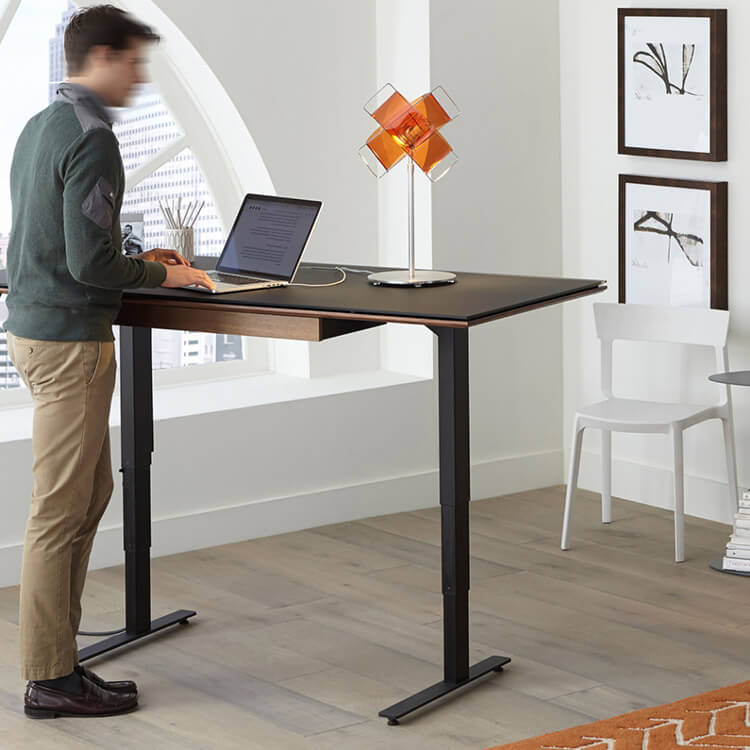 Man standing on an adjustable office desk for ergonomic work setup.