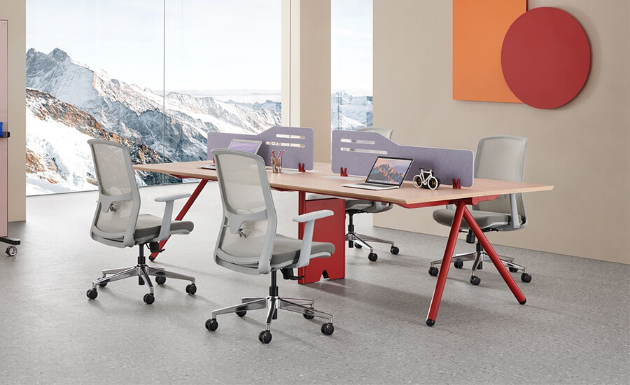 A four-person desk with flaps and four grey-mesh office chairs in office.